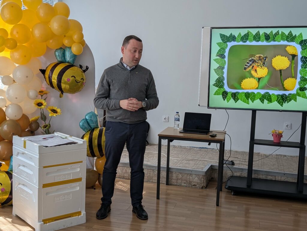 Мъж представя STEM урок пред постер с пчели